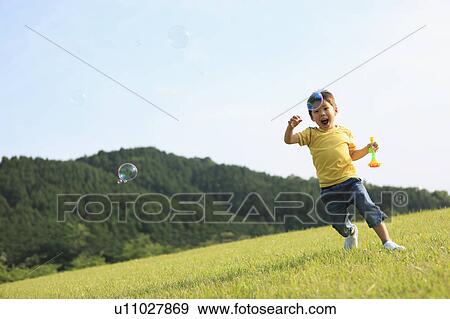 Young Boy Running After Soap Bubbles View Large Photo Image Stock Photo - Young Boy Running After Soap Bubbles. Fotosearch