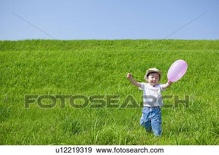 Stock Photo - Young Boy Running With Balloon in Field. Fotosearch