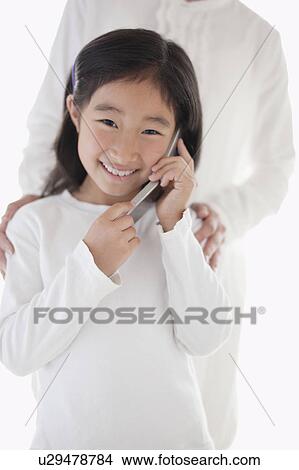 Picture - Young Girl on the Phone, Mother in the Background. Fotosearch