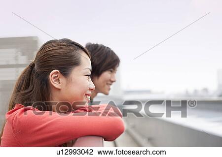 Stock Image - Young man and woman on rooftop, Japan. Fotosearch