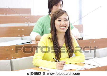 Stock Image - Young man and young woman studying in classroom, Japan. Fotosearch