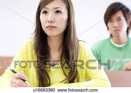 Stock Image - Young man and young woman studying in classroom, Japan. Fotosearch