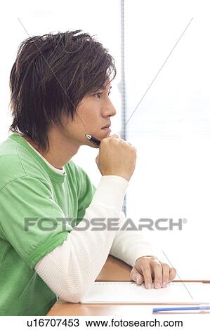 Stock Image - Young man studying in classroom, Japan. Fotosearch