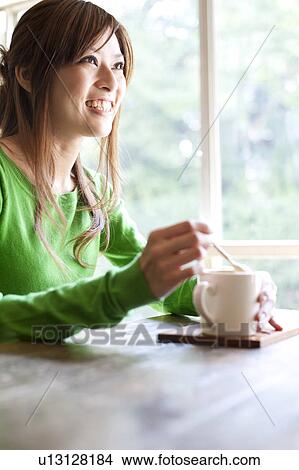 Picture - Young woman at a cafe drinking coffee, Japan. Fotosearch
