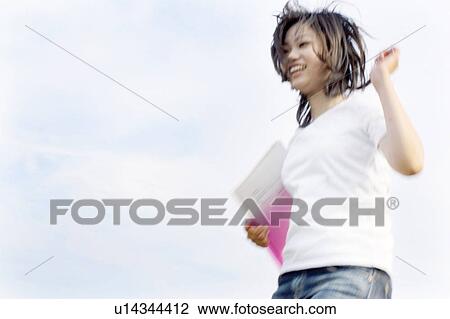 Young woman holding a file and jumping View Large Photo Image Stock Image - Young woman holding a file and jumping. Fotosearch