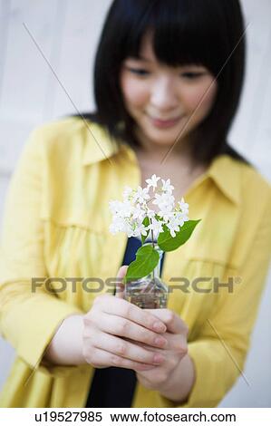 Young Woman Holding a Stem of Flowers View Large Photo Image Stock Photography - Young Woman Holding a Stem of Flowers. Fotosearch