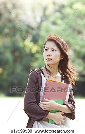 Stock Photo - Young woman holding books, Japan. Fotosearch