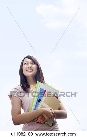 Stock Image - Young woman holding notebooks, copy space. Fotosearch