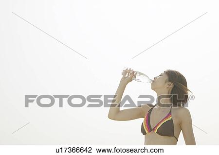 Young woman in bikini drinking bottle of water, white background, copy space View Large Photo Image Stock Image - Young woman in bikini drinking bottle of water, white background, copy space. Fotosearch