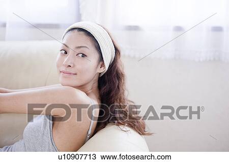 Young woman leaning on sofa, looking back View Large Photo Image Stock Image - Young woman leaning on sofa, looking back. Fotosearch