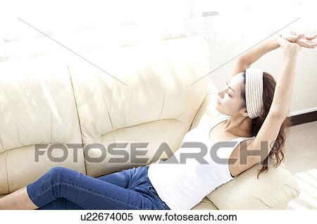 Young woman leaning on sofa, stretching View Large Photo Image Stock Photography - Young woman leaning on sofa, stretching. Fotosearch