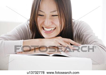 Stock Photo - Young Woman Looking at Notebook, Smiling. Fotosearch