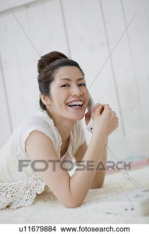 Picture - Young Woman Lying on Floor and Talking on the Phone. Fotosearch