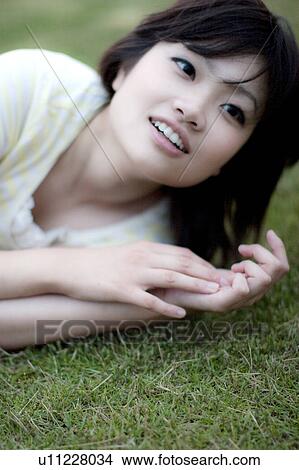 Picture - Young woman lying on grass. Fotosearch