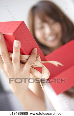 Stock Photography - Young woman opening present box, close up, white background, differential focus. Fotosearch