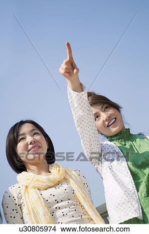 Young Woman Pointing Something to her Friend View Large Photo Image Picture - Young Woman Pointing Something to her Friend. Fotosearch