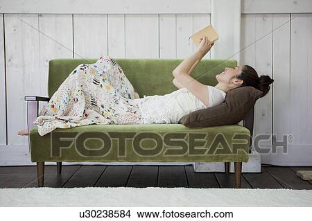 Young Woman Reading Book on Sofa View Large Photo Image Picture - Young Woman Reading Book on Sofa. Fotosearch