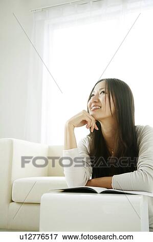 Stock Photo - Young Woman Resting Her Chin on Hand, Looking Up. Fotosearch