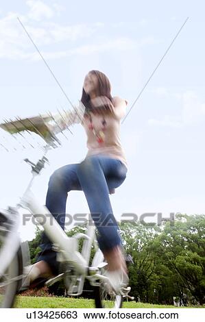 Stock Image - Young woman riding bicycle, blurred motion. Fotosearch