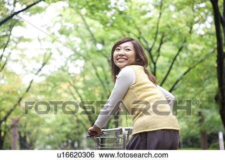 Young woman riding bicycle, smiling View Large Photo Image Stock Photograph - Young woman riding bicycle, smiling. Fotosearch