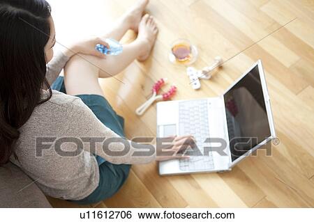 Young woman sitting of floor, using laptop View Large Photo Image Stock Photograph - Young woman sitting of floor, using laptop. Fotosearch