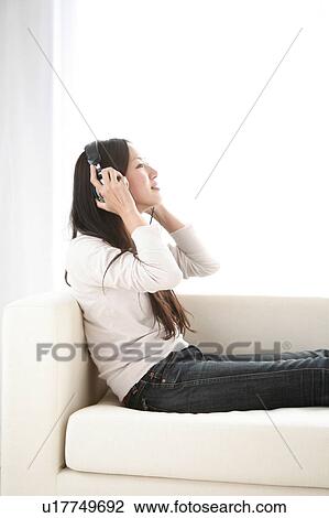 Young Woman Sitting on Sofa, Listening to Music View Large Photo Image Stock Image - Young Woman Sitting on Sofa, Listening to Music. Fotosearch