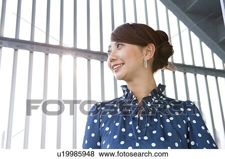 Stock Photo - Young woman smiling and looking away. Fotosearch