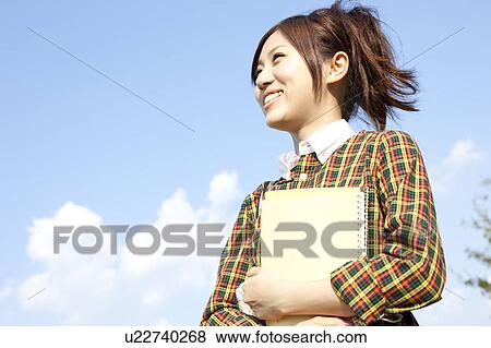 Young woman standing holding note pad, Japan View Large Photo Image Stock Photo - Young woman standing holding note pad, Japan. Fotosearch
