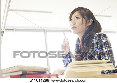 Stock Photo - Young woman studying in a library, Japan. Fotosearch