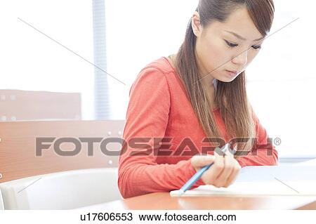 Stock Image - Young woman studying in classroom, Japan. Fotosearch