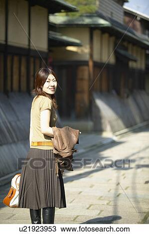Young Woman Walking on Street and Looking Back View Large Photo Image Stock Image - Young Woman Walking on Street and Looking Back. Fotosearch