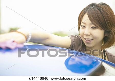 Stock Photograph - Young woman washing car, smiling. Fotosearch