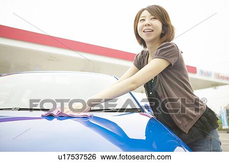 Stock Photograph - Young woman washing car, smiling. Fotosearch