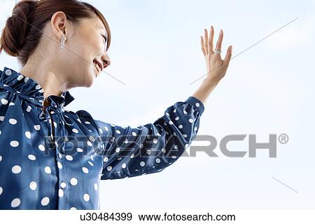 Young woman waving hand, smiling View Large Photo Image Stock Photo - Young woman waving hand, smiling. Fotosearch