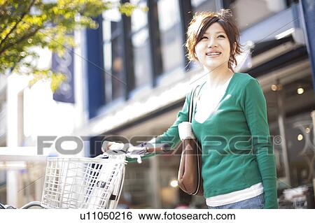 Stock Photograph - Young woman with a bicycle, Japan. Fotosearch