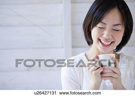 Stock Image - Young Woman With Coffee Cup Laughing. Fotosearch