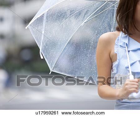Stock Image - Young woman with umbrella, differential focus. Fotosearch
