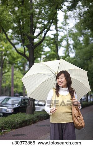 Stock Photograph - Young woman with umbrella, smiling. Fotosearch
