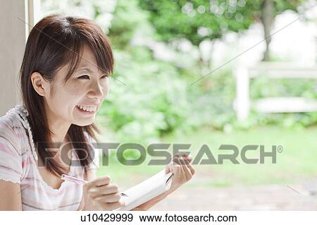Young woman writing on note pad and smiling, Japan View Large Photo Image Stock Photo - Young woman writing on note pad and smiling, Japan. Fotosearch