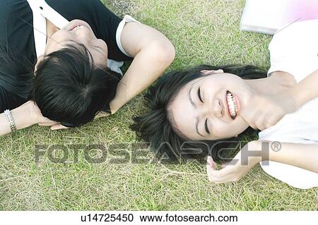 Stock Image - Young women lying on grass, directly above. Fotosearch