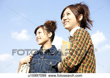 Young women standing holding note pad, Japan View Large Photo Image Stock Photo - Young women standing holding note pad, Japan. Fotosearch