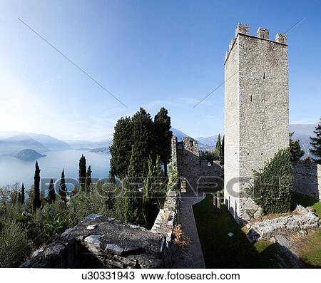 Aerial stitched panorama from Castello di Vezio showing interior courtyrd and crenellated stone tower, with views across cypress and olive trees to Lake Como, shrouded in early morning mist, with mountain range beyond, on sunny autumn morning, Northern It View Large Photo Image Stock Image - Aerial stitched panorama from Castello di Vezio showing interior courtyrd and crenellated stone tower, with views across cypress and olive trees to Lake Como, shrouded in early morning mist, with mountain range beyond, on sunny autumn morning, Northern It. Fotosearch
