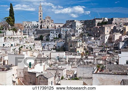 Aerial view of ancient town of Matera with tufa houses, and Duomo on hill beyond, sunny spring afternoon with blue sky, Puglia, Southern Italy View Large Photo Image Stock Photography - Aerial view of ancient town of Matera with tufa houses, and Duomo on hill beyond, sunny spring afternoon with blue sky, Puglia, Southern Italy. Fotosearch