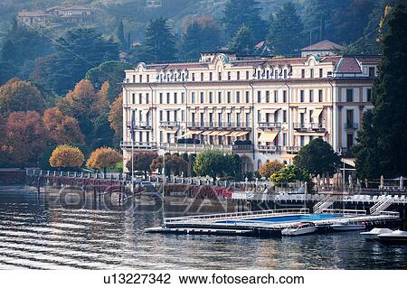 Aerial view of ornate facade of Villa d'Este facing Lake Como, rippling waves of motorboats, some moored, autumn colours of lush ornamental gardens, Northern Italy View Large Photo Image Stock Image - Aerial view of ornate facade of Villa d'Este facing Lake Como, rippling waves of motorboats, some moored, autumn colours of lush ornamental gardens, Northern Italy. Fotosearch