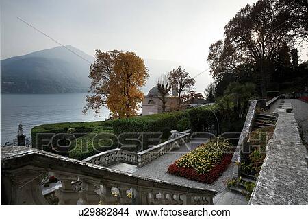 Aerial view of Villa Carlotta ornamental gardens, terraced stairways, flowerbeds and horsechestnut trees in autumn colours, with view over lake to mountains, Lake Como, Northern Italy View Large Photo Image Picture - Aerial view of Villa Carlotta ornamental gardens, terraced stairways, flowerbeds and horsechestnut trees in autumn colours, with view over lake to mountains, Lake Como, Northern Italy. Fotosearch