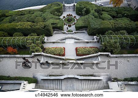 Stock Photograph - Aerial view of Villa Carlotta showing ornamental gardens, terraced stairways, fountain with statue and lake front beyond ornate wrought iron gateway, Lake Como, Northern Italy. Fotosearch