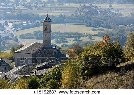 Stock Photo - Aerial view of village stone church with bell tower, slate roofs, and autumn colours of trees, with plain below of planted fields, Lombardy, Italy. Fotosearch