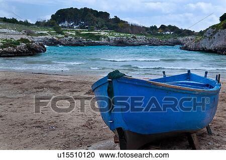 Beached blue wooden fishing boat on sandy shore of Porto Badisco inlet, with rocky shore line, blue sky, Salento, Puglia, Southern Italy View Large Photo Image Stock Image - Beached blue wooden fishing boat on sandy shore of Porto Badisco inlet, with rocky shore line, blue sky, Salento, Puglia, Southern Italy. Fotosearch