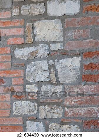 Stock Image - Close up detail of wall of house, showing traditional building technique using combination of red brick and local grey stone, creating texture and pattern. Fotosearch