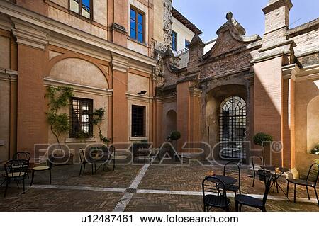 Stock Image - Detail of inner courtyard of Italian Renaissance palazzo, with arches, windows, patterned pavimenti brick design, and ornamental wrought iron gate, brick and stucco, Todi, Umbria. Fotosearch